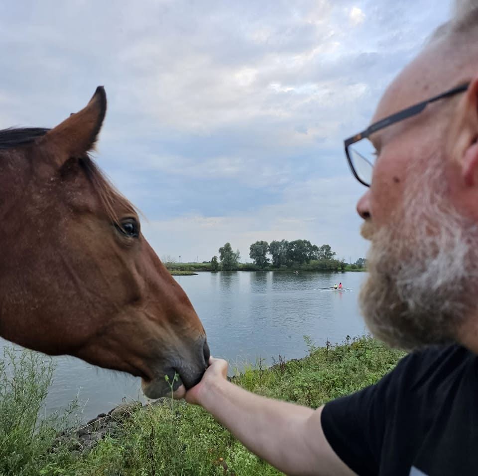 Iwan buiten aan het water, voert een paard uit zijn hand.