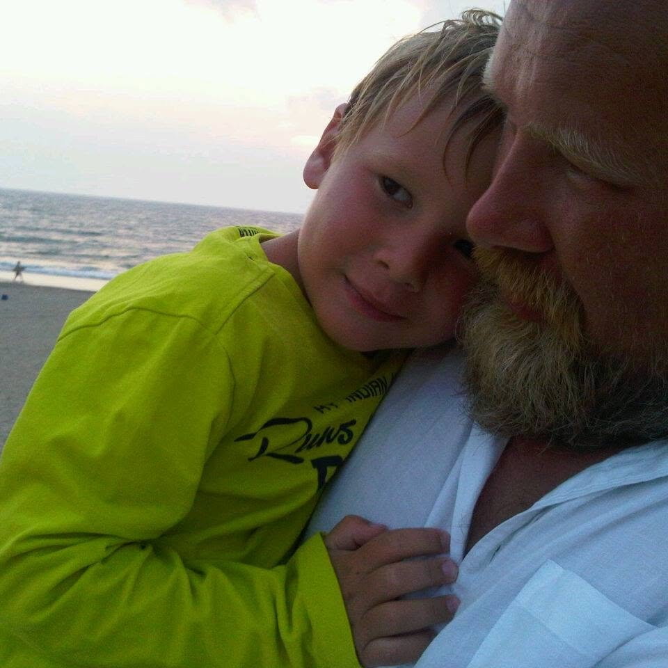 Iwan aan het strand met zijn zoon tegen zich aan.